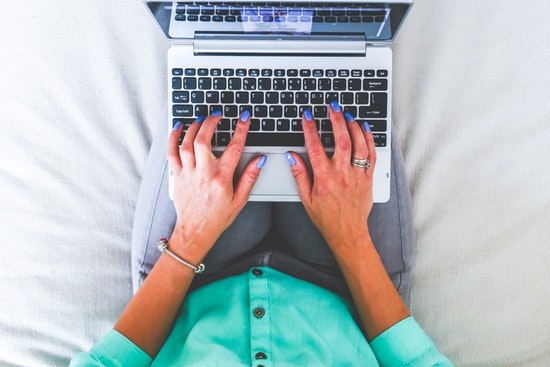 Person sitzt auf couch und tippt am Laptop